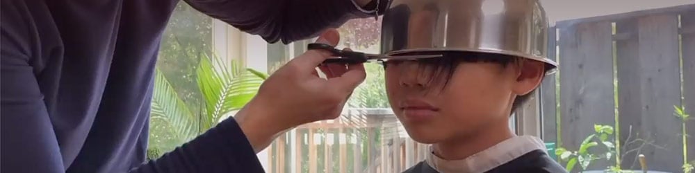 Image of a boy having a bowl haircut by his father