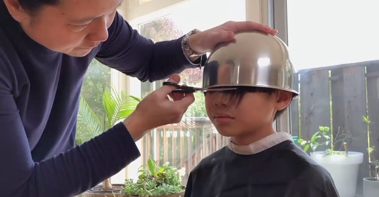 Image of a boy having a bowl haircut by his father
